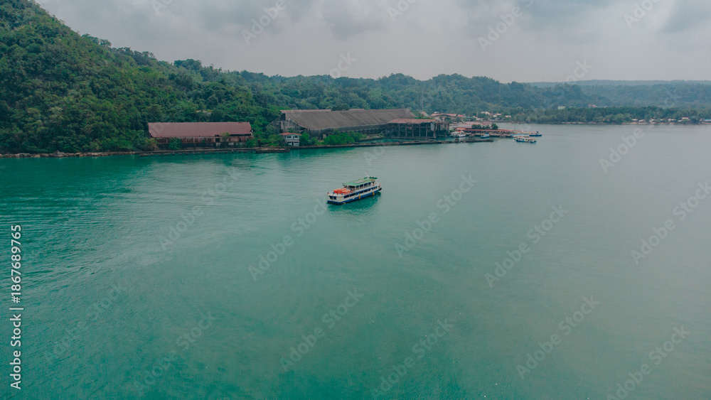 Fototapeta premium Verdant Voyage: Lone Ferry Crossing Jade Waters In Guimaras, Philippines