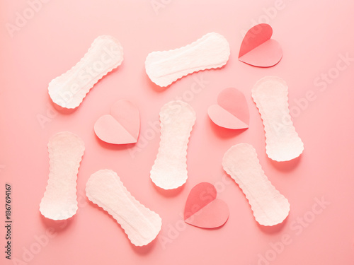 Seamless pattern of white sanitary pads and red paper hearts on pink background menstruation and feminine hygiene concept
