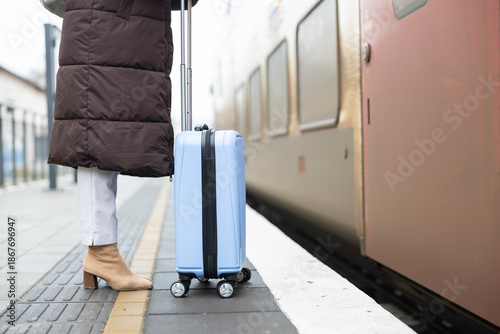 Tableau sur toile A traveler stands ready to board the train, suitcase in tow, preparing for her next adventure ahead
