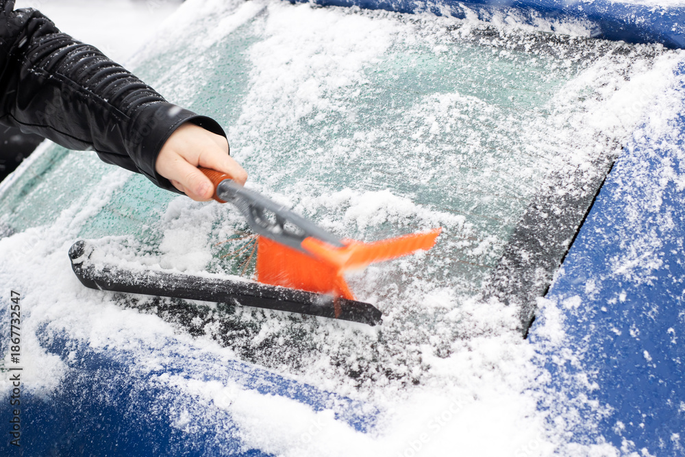 Fototapeta premium Person quickly removing ice from vehicle, Frosty morning routine to clear icy windshield safely