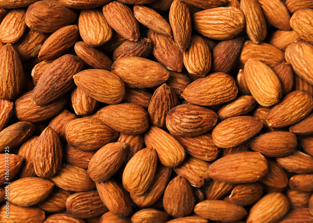 Fototapeta premium Full frame background of roasted almond nuts, close-up texture of brown kernels