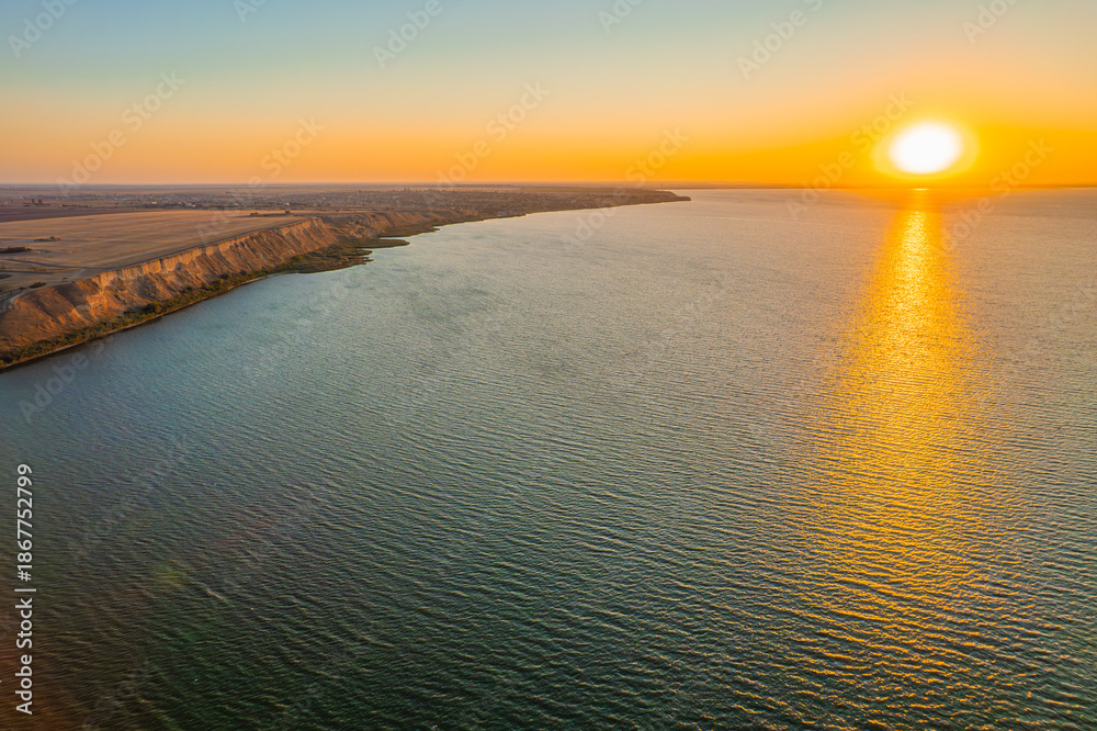 Obraz premium Sunset over calm sea with golden reflection on water surface