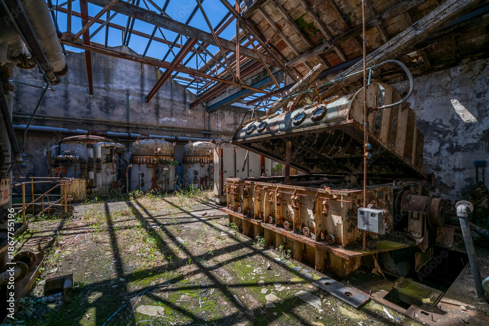Fototapeta premium Derelict industrial hall of an abandoned Italian sugar mill. Large warehouse ruins with decaying walls and urban exploration atmosphere