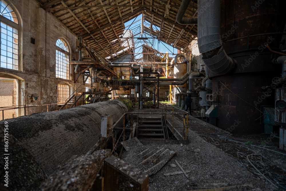 Fototapeta premium Vintage machinery inside an abandoned sugar refinery in Italy. Rusted equipment and industrial decay in a defunct factory hall