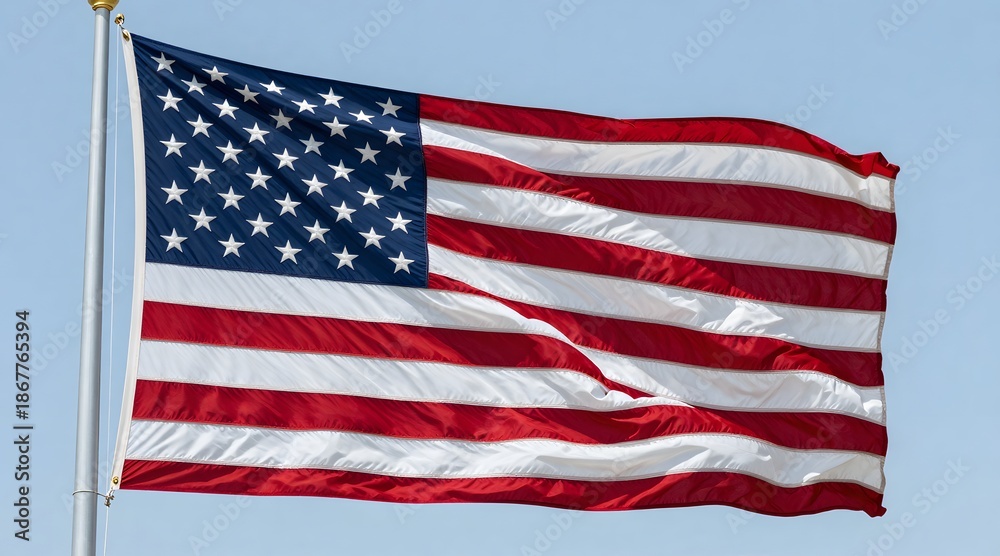 Fototapeta premium American flag waves proudly against a clear blue sky, symbolizing freedom and patriotism