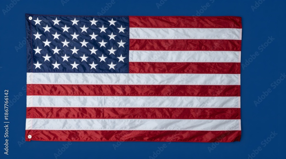 Fototapeta premium United states flag with stars and stripes lies against solid blue background