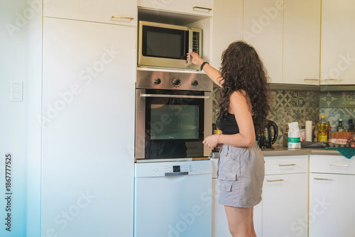 Middle-aged woman in her kitchen baking, she is opening the oven