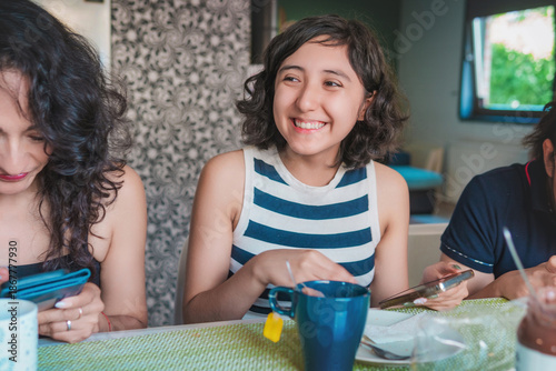 Happy young Latin women enjoying a healthy breakfast while seated in the dining room of their modern apartment. Healthy lifestyle and nutrition concept.