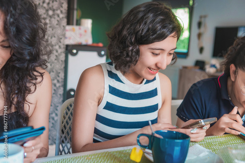 Happy young Latin women enjoying a healthy breakfast while seated in the dining room of their modern apartment. Healthy lifestyle and nutrition concept.
