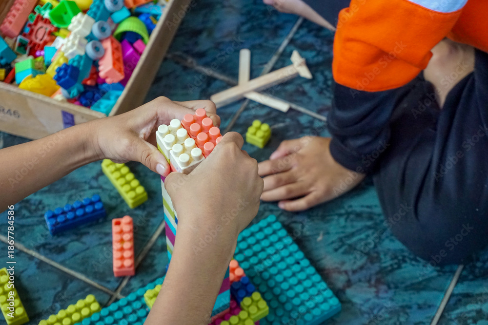Naklejka premium Children are playing with colorful plastic building blocks on the tiled floor, creativity and interaction as they play with these educational toys