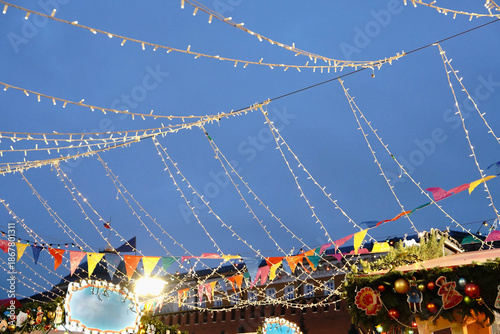 Canvas Print Festive street decoration with hanging overhead string lights and colorful bunti
