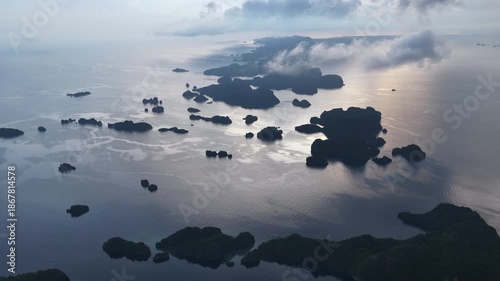 A cloudy sunrise illuminates scenic limestone islands in Misool, Raja Ampat. This beautiful Indonesian area is a popular destination for divers and snorkelers due to its incredible marine biodiversity