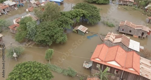 Aerial view of a flooded Cambodian village with traditional houses partially submerged in murky water.
