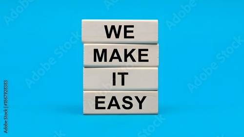 Four white wooden blocks stacked vertically on a blue background spelling out the phrase 'WE MAKE IT EASY', symbolizing simplicity and convenience.
