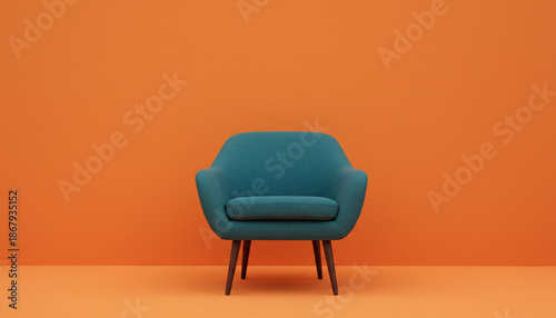 A modern teal armchair with wooden legs against a vibrant orange background.
