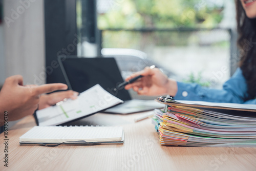 Business transaction at desk: A focused, professional interaction unfolds as two individuals exchange documents. The scene captures the essence of a deal being made. 