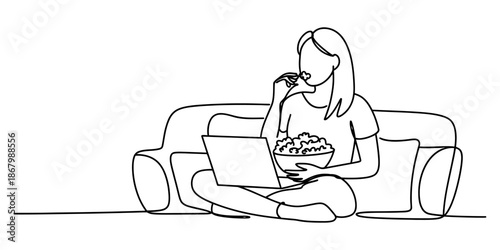 A woman enjoys leisure time at home watching content on a laptop and eating popcorn