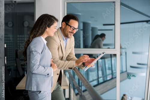 Business professionals discussing chart on tablet in modern office
