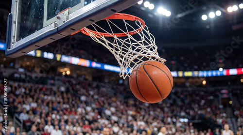 Basketball hoop net stadium sport competition crowd teamwork ball dropping through hoop in dramatic game moment