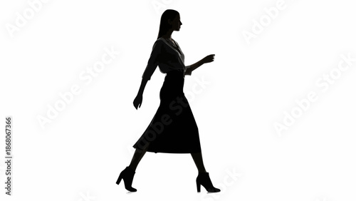 Silhouette of a woman walking confidently in a dress and heels.