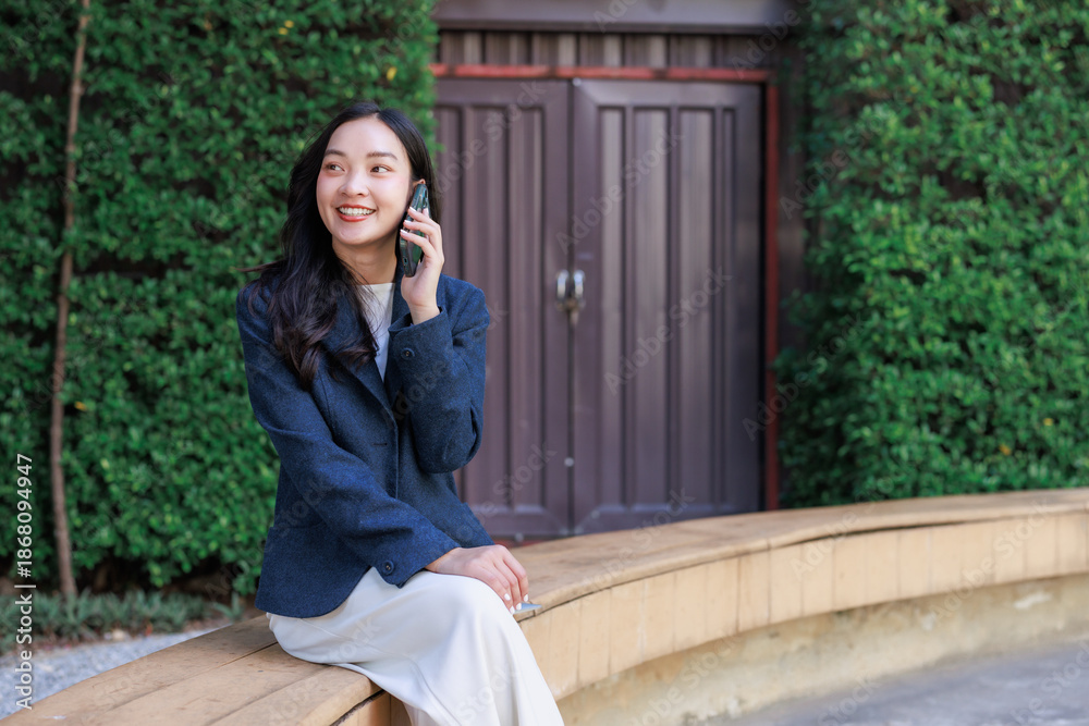 Fototapeta premium Young asian woman smiling having mobile phone conversation