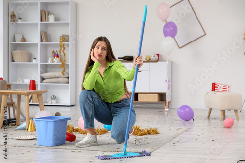 Upset young woman with mop ...