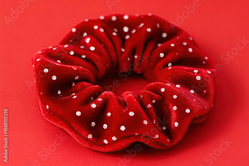 Close up of a vibrant red velvet scrunchie with small white polka dots