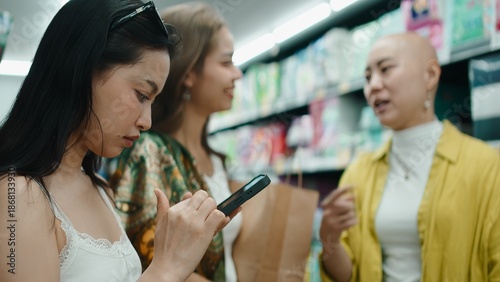 Photography Asian friends buying groceries, browsing phone and chatting in a bangkok store