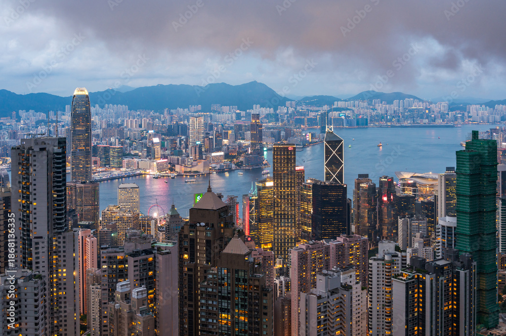 Naklejka premium View of Hong Kong and Kowloon from Victoria peak. Evening, sunset. Panorama of Hong Kong, skyscrapers and nature. 21 May 2025, Hong Kong, China