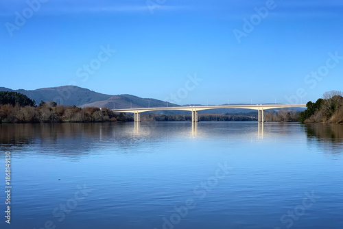 Foto Scenic Ponte da Amizade bridge crossing wide river Minho under clear blue sky, V