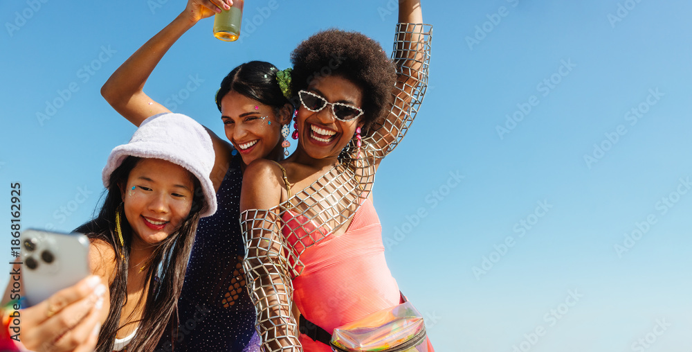 Fototapeta premium Friends take a sunny carnival selfie on the beach