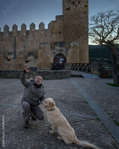 Happy man taking selfie with Golden Retriever dog at medieval Frias castle in Burgos Spain