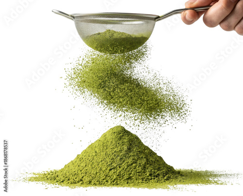 A hand sifts green powder through a sieve, creating a cloud above a mound of fine, vibrant green substance on a dark background.