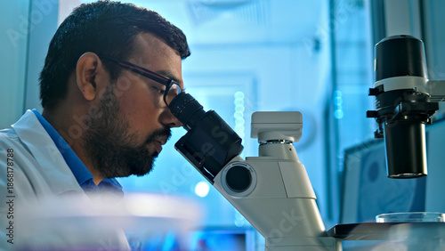 Fotografie A researcher examines a sample under a microscope in a modern lab, highlighting meticulous scientific investigation and precision in medical research