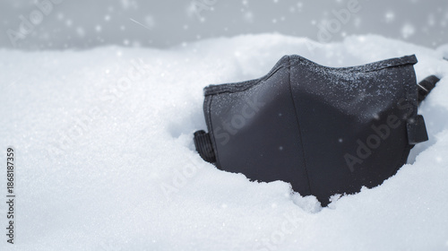 Mask Half-Buried in Soft Snow, Symbolizing Resilience and Change in a Winter Landscape Where Nature's Silence Prevails