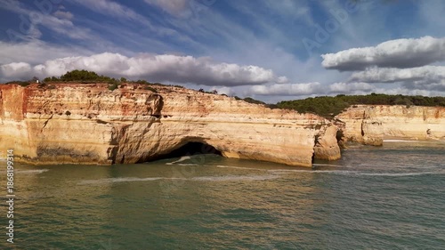 Aerial Approach Over the Atlantic Ocean Towards the Iconic Benagil Sea Cave and Rugged Limestone Coastline of the Algarve in Portugal