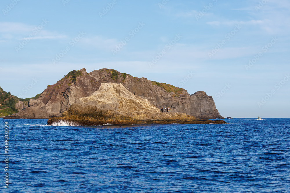 Fototapeta premium 沖磯に釣人がいる。 夕暮れの海に漁船に乗ってアカハタ釣りに出かけた。 ヒリゾ浜南伊豆町中木 静岡県伊豆半島-2025 日本有数のシュノーケリングスポット。 夏の数カ月間だけ渡し船で行ける。 水質透明度魚影が素晴らしい。 