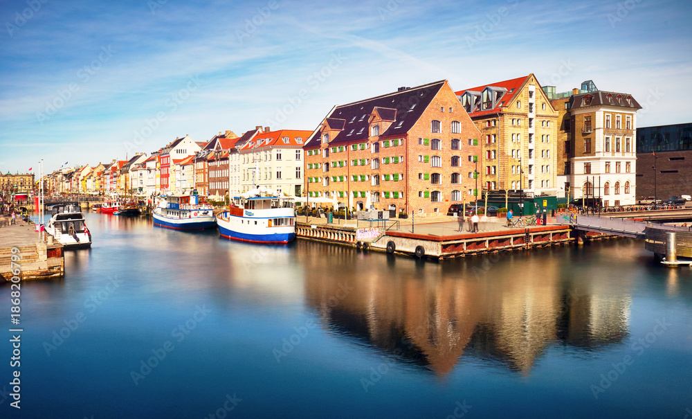Obraz premium River canal with many boats and ships with small old houses in the neighbourhood area Christianshavn in Copenhagen, Denmark
