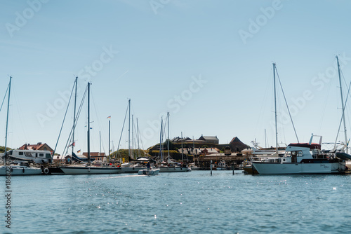 Scenic view of Varberg harbor with sailboats and the historic Varberg Fortress under a clear blue sky, Sweden