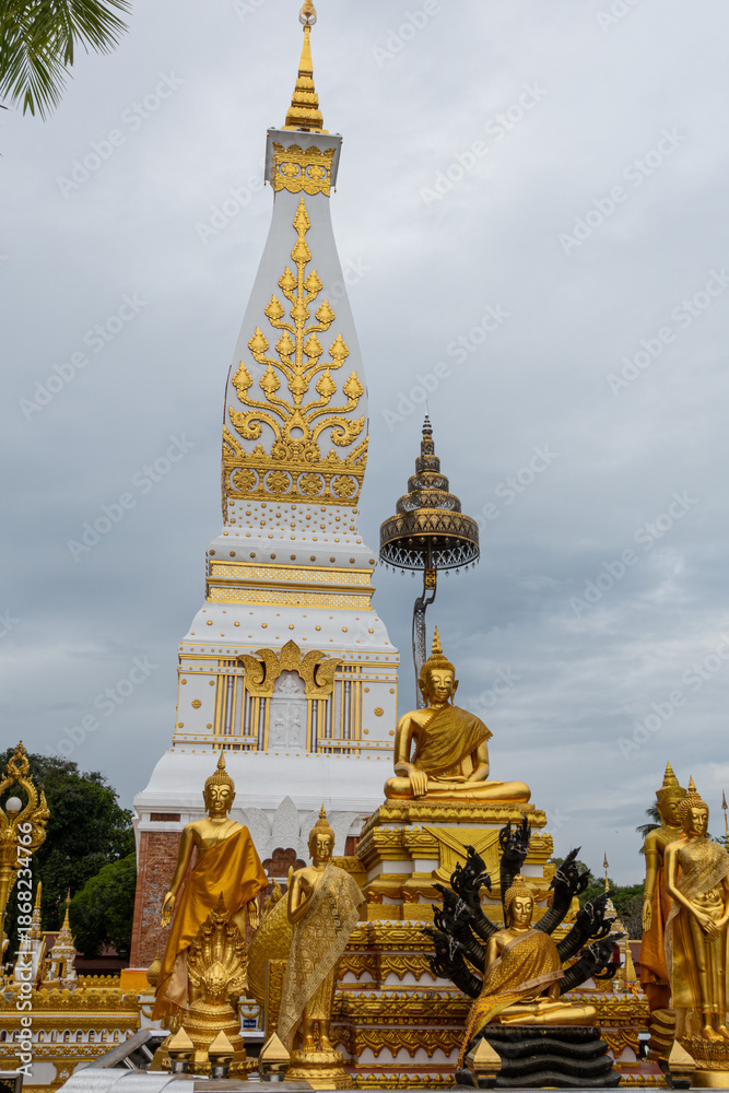 Fototapeta premium Phra That Phanom, iconic Buddhist stupa with golden carvings and white architecture, rising against a bright blue sky. Sacred Thai temple landmark, rich cultural heritage and spiritual atmosphere