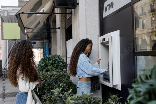 Bild auf Leinwand Young women using atm for cash withdrawal