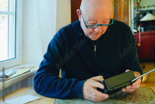 Quiet independence and mindful technology of senior lifestyle  using a portable radio , focused attention and simple interaction reflecting confidence with everyday devices in retired age.