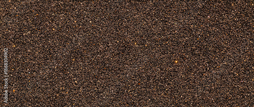 Close-up macro view of dark brown sand with subtle golden sparkles and texture