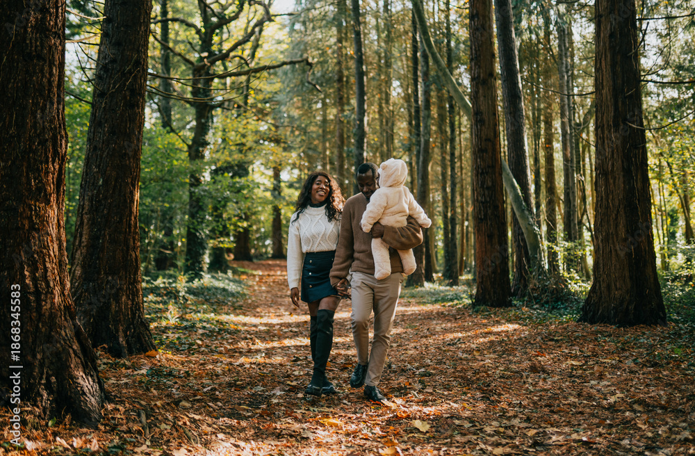 Fototapeta premium A couple and their child are walking through a forest. The man is holding a teddy bear