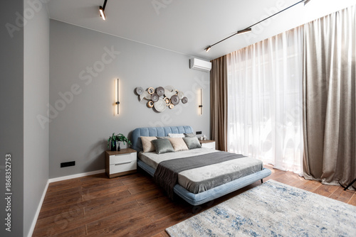 Foto A bedroom with a blue bed, white pillows, and a gray blanket
