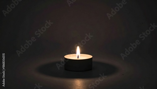 Lit candle on black background with light coming from the top candle.