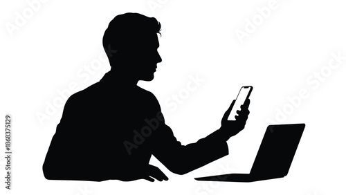 Silhouette of a professional businessman checking messages on a mobile phone next to a laptop