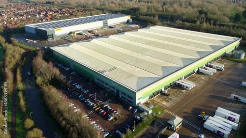 Milton Keynes, United Kingdom - 20 December 2025: Aerial view of a DHL distribution center, showing trucks and cars in a vast landscape.