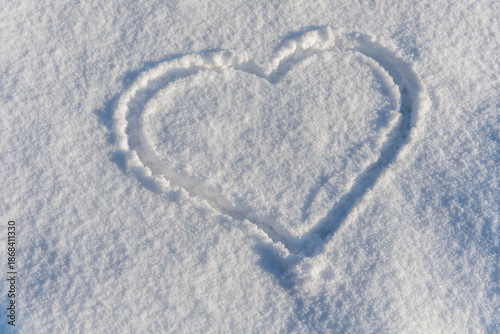 Heart shape drawn in fresh white snow. Simple and romantic winter symbol representing love, Valentines Day, and peaceful seasonal emotions in a snowy landscape