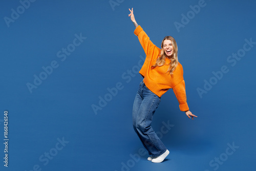 Quadro su tela Full body young happy woman she wearing yellow sweater casual clothes standing on toes dancing lean back have fun spreading hands isolated on plain blue background studio portrait